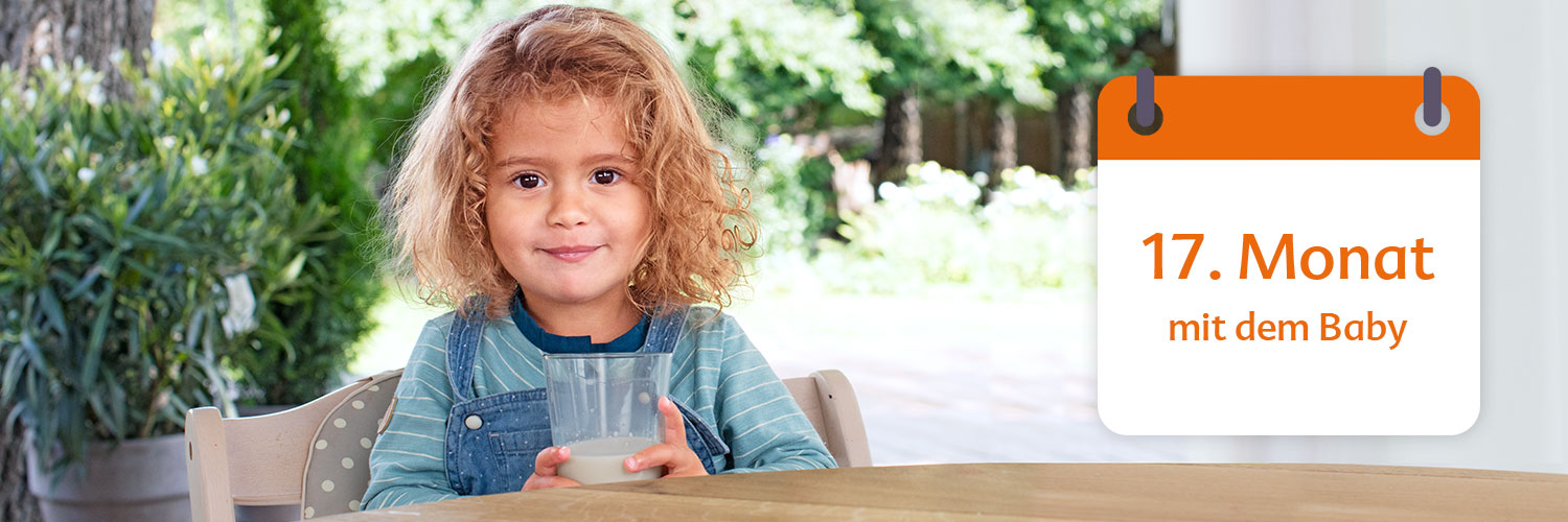 A young child with curly hair sits at a table holding a glass of milk, with a calendar indicating '17. Monat mit dem Baby' in the background.