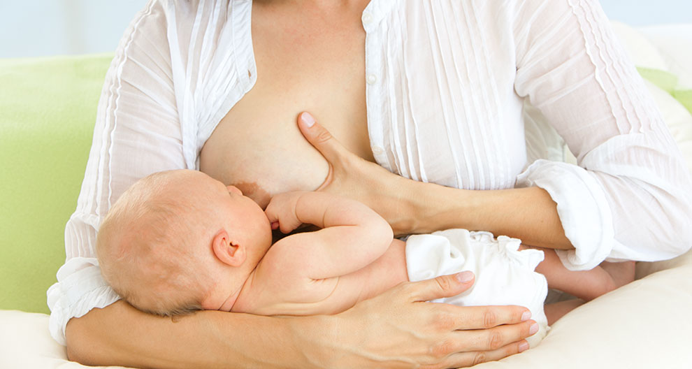 A woman in a white shirt is breastfeeding a baby.