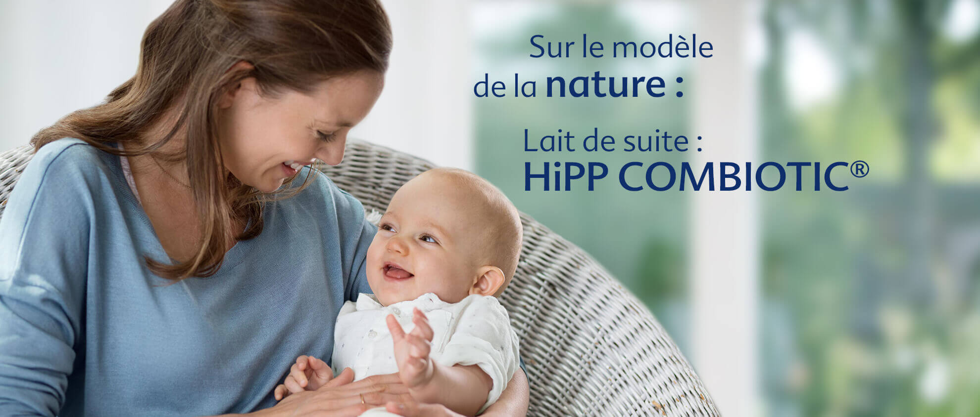 Une femme en chemise bleue tient un bébé, avec un texte en français faisant la promotion d'un produit appelé "HiPP COMBIOTIC®".
