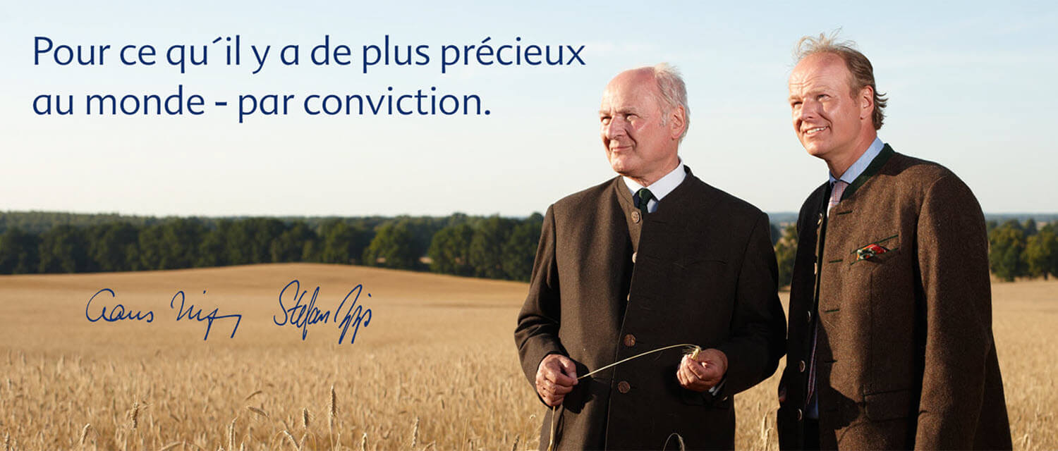 Deux hommes en costume se tiennent dans un champ avec une citation et une signature en français.