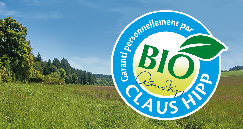 Un paysage avec des arbres et de l'herbe est superposé à un logo circulaire comportant le mot "BIO" et le nom "Claus Hipp".