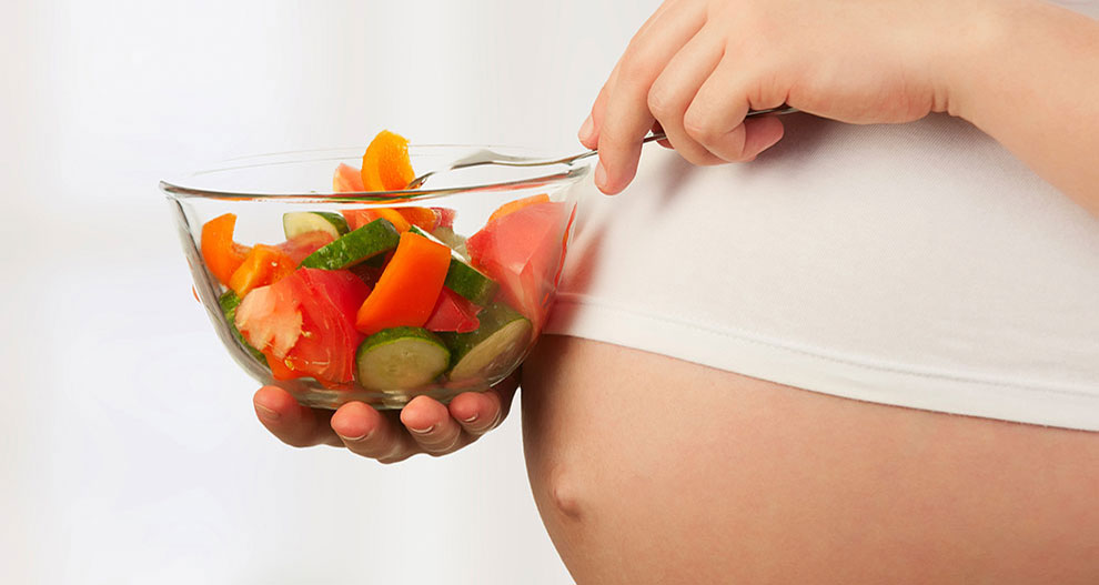 Une personne mange un bol de légumes frais.