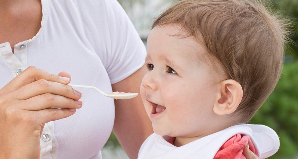 Une personne nourrit un bébé avec une cuillère.