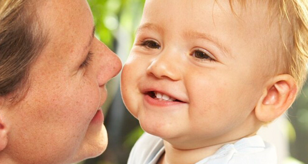 Gros plan d'une femme et d'un bébé, le visage de la femme étant partiellement visible et celui du bébé étant bien visible, se regardant l'un l'autre.