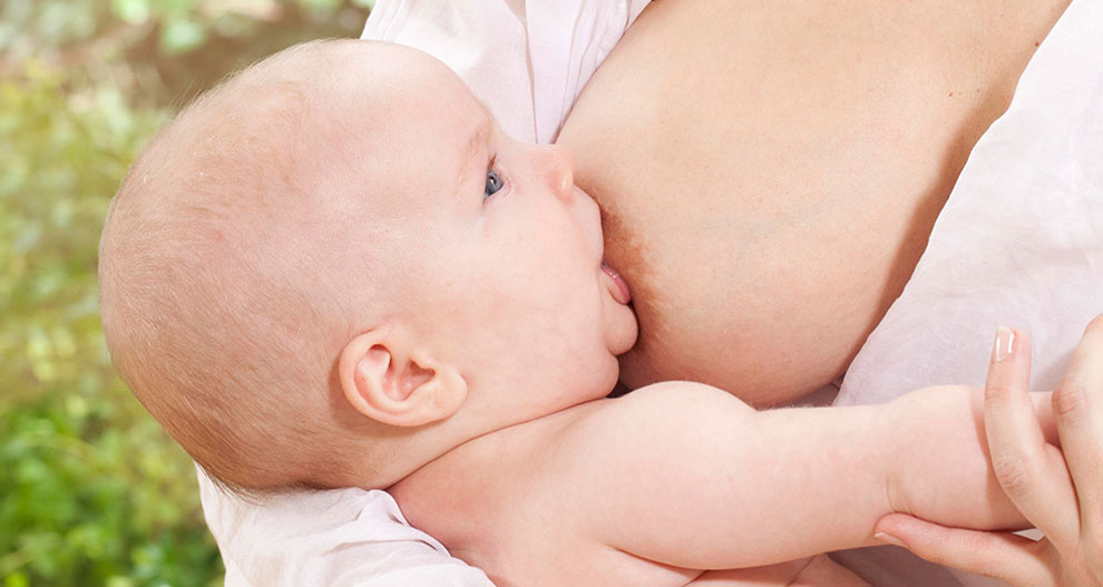 Un bébé est allaité par une femme.