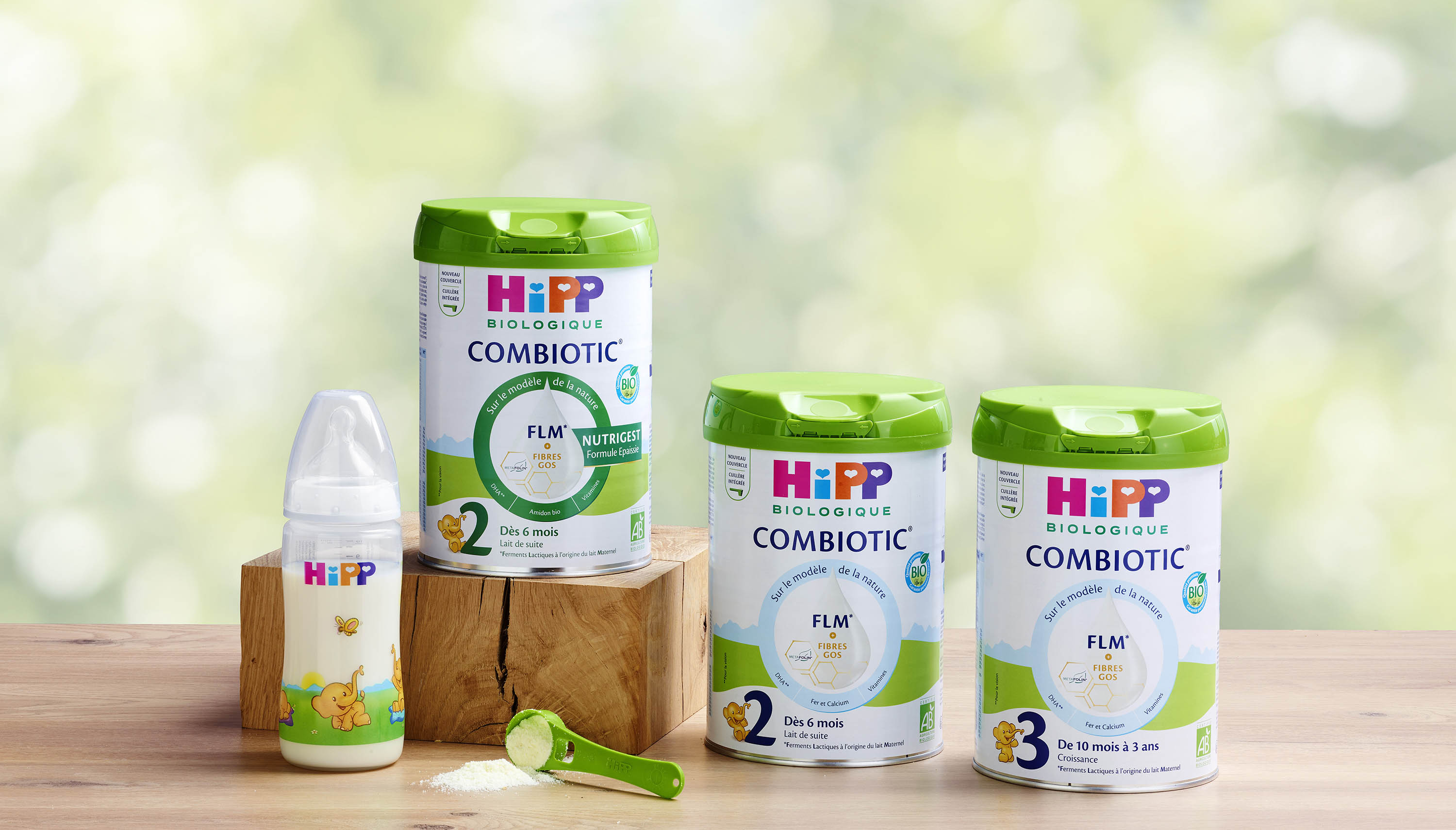 Trois boîtes de lait maternisé Hipp Combiotic, un biberon avec du lait maternisé et une cuillère de lait maternisé en poudre.