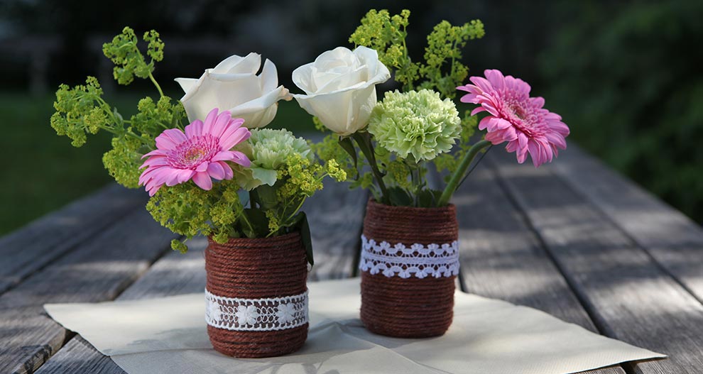 Deux vases avec des fleurs sur une table.