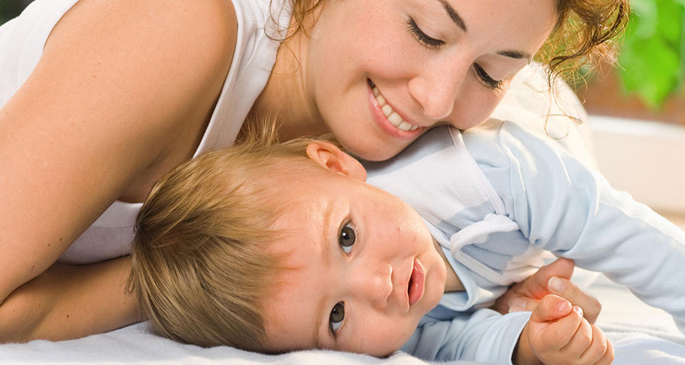 Une femme et un bébé sont allongés sur un lit.