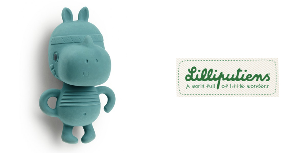 Une figurine de couleur sarcelle avec un visage souriant et un bandeau décoratif se trouve à côté d'un logo vert et blanc indiquant "Lilliputiens - Un monde plein de petites merveilles".