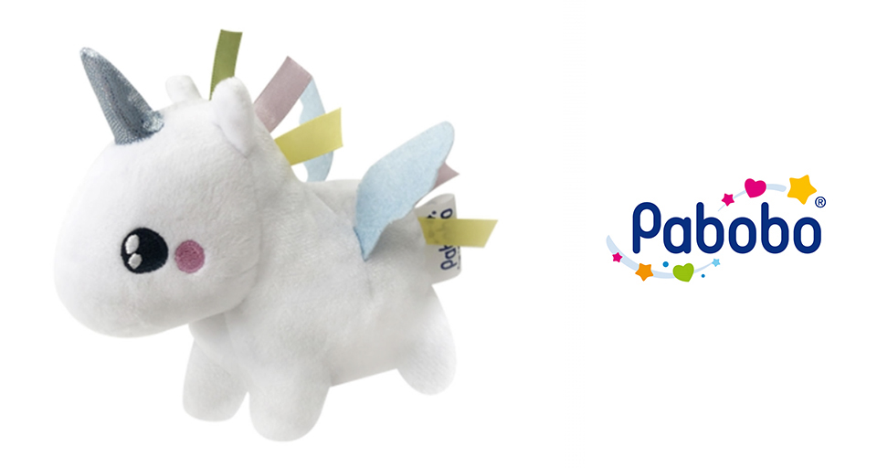 Une licorne en peluche blanche avec des rubans de couleur pastel et une étiquette portant la mention "Pabobo" est exposée à côté du logo Pabobo, qui présente un fond bleu avec des étoiles et des cœurs colorés.