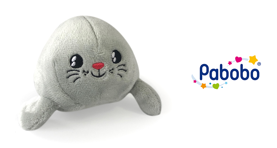 Une peluche de phoque gris est placée à côté d'un logo coloré avec le mot "Pabobo" et des éléments décoratifs.